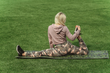 Beautiful sport woman doing stretching fitness exercise in city park at green grass