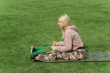 Beautiful sport woman doing stretching fitness exercise in city park at green grass