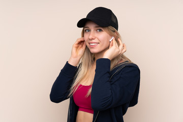 Young sport blonde woman over isolated background listening music