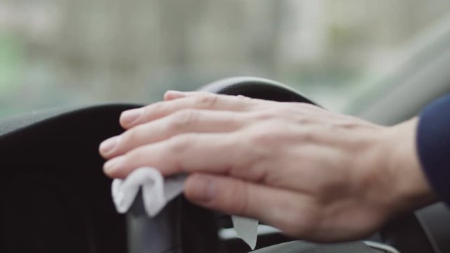 Driver using wet wipe for disinfecting car steering wheel against Novel coronavirus or Corona Virus Disease (Covid-19)