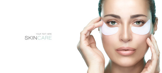 Eyes cosmetic mask. Beautiful young woman with healthy fresh skin using patches under eyes.