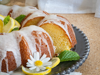 Lemon Ricotta Bundt Cake with icing displayed on a black decorative plate in a light bright airy setting.