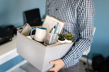 Midsection close up of unknown caucasian man holding a box with personal items stuff leaving the...