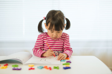 toddler girl practice writing letters for homeschooling