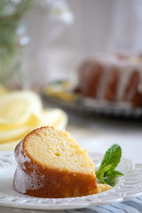 A slice of moist Lemon Ricotta Bundt Cake on a white decorative plate with a mint leaf garnish.