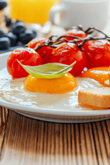 Homemade fried eggs with tomatoes, fresh summer fruits, berries, coffee and juice