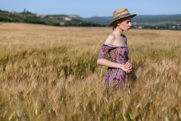 Naklejka na ściany i meble Beautiful fashionable blonde woman in a field of wheat
