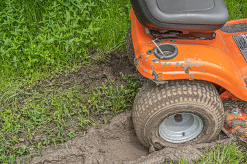 Obraz premium Dike, Texas, USA - April 9, 2020 - Lawn mower stuck in a muddy rut.