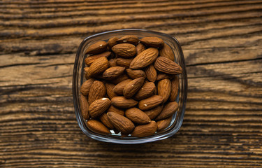 Almonds in a small plate on a vintage wooden table as a background. Almond is a healthy vegetarian protein nutritious food. Natural nuts snacks.
