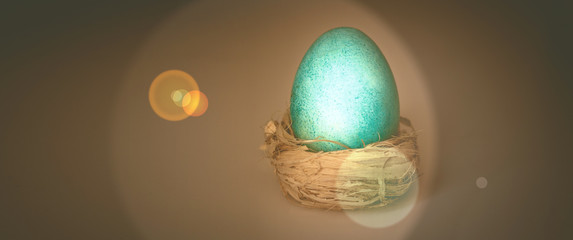 Art photo of a blue egg on a dark background with sun flare. Egg as a symbol of life and Easter.
