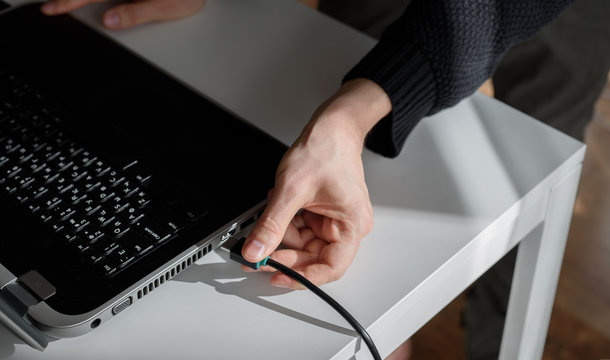 a man plugs a HDMI cable into a laptop with his hand