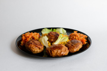 Fried chicken cutlet with potato slices served with tomato cherry and corn salad. Traditional belorussian food - roasted minced meat and potato