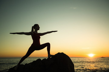 Yoga silhouette of woman on the sea beach at amazing sunset.