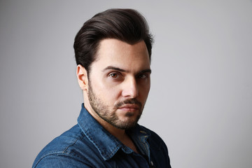 Portrait of 30-year-old man standing over grey background in denim shirt. Close up. Copy-space. Studio shot.
