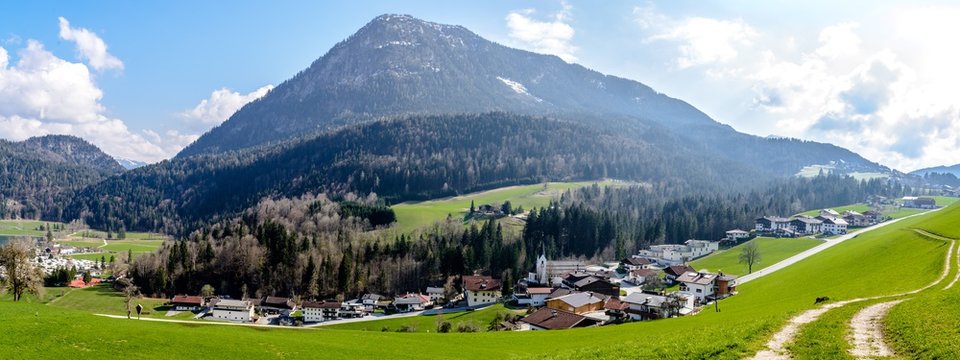 Alps mountains by lake Thiersee nearby Kufstein, mountain Barenhohle, Mittagskopf, blue sky, green field, church, houses. Tyrol, Austria. Panorama view 
