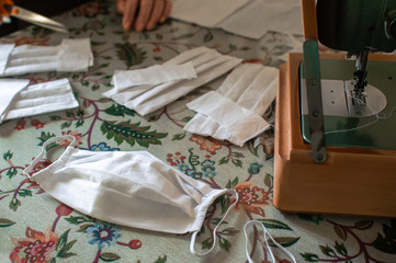 Woman making a protective mask at home during quarantine for coronavirus. Handmade mask, sewing machine and materials to make one.