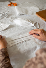 Woman make a protective mask at home. View of person sewing medical mask because the lack of stock in stores during quarantine for coronavirus.