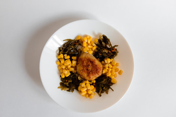 Fried chicken cutlet with potato slices served with tomato cherry and corn salad. Traditional belorussian food - roasted minced meat and potato