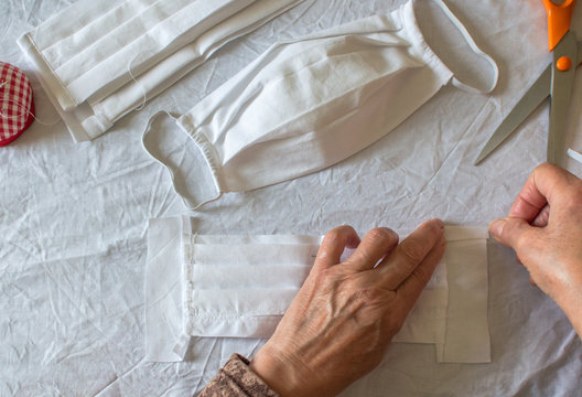 Top view of woman make a protective mask at home against coronavirus. Person sewing medical mask because the lack of stock in stores, close up. Copy space left.