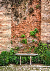 a very old stone bench in a garden in front of a wall with plants growing on it