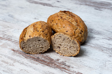Top view of two fresh healthy loaves of multi-grain seedy bread on rustic wooden table. Homemade sliced and whole loaves of bread close-up. Baking and home bread making background, concept, copy space