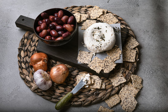 Greek Kalamata Olives With Seeded Crackers, And Non Dairy Cheese Spread On Woven Mat Side View, Horizontal Orientation.