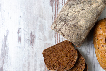Top view of fresh healthy multi-grain seedy and rye bread on rustic wooden table. Assorted loaves of bread close-up, whole and sliced. Background, idea, concept, copy space