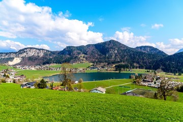 Fototapeta na wymiar Beautiful view on lake Thiersee, alps Mountains, houses, church, blue sky, green fields. Austria, Tyrol. Border with Bavaria, Germany