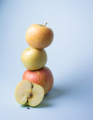 tower from yellow and red apples on cold blue background