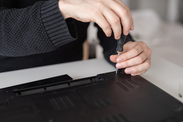 A man disassembles a laptop. Computer service and repair concept. Laptop disassembling in repair shop, close-up. Electronic development, electronic device fixing