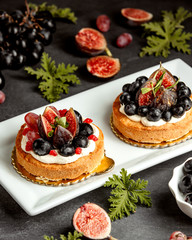 two small pies decorated with figs blueberries and grapes