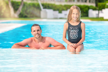 Family of mom and little daughter enjoying summer vacation in luxury swimming pool