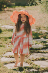 Baby girl in a striped dress with a pink hat.