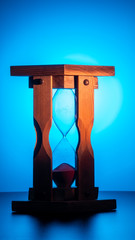 expired wooden hourglass on a blue gradient background. the upper vessel of the clock is...