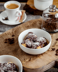 a bowl of profiteroles topped with chocolate sauce and coconut sprinkles
