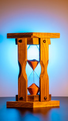 running wooden hourglass in orange warm color. bright blue pink round gradient background.