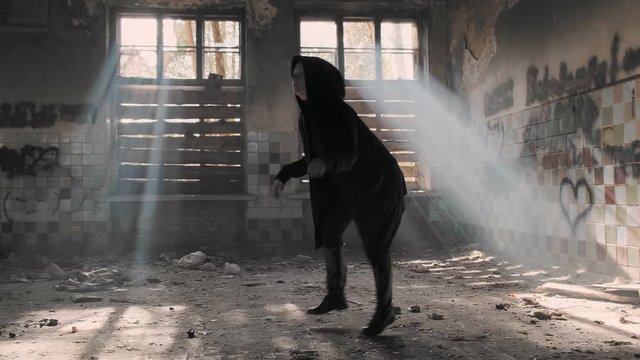 woman performs dinosaur dance in sun beam in abandoned building.