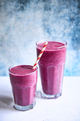 Two glasses of pink smoothie with straw