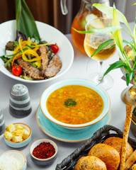 a lunch setup with vegetable soup salad bread and cocktail