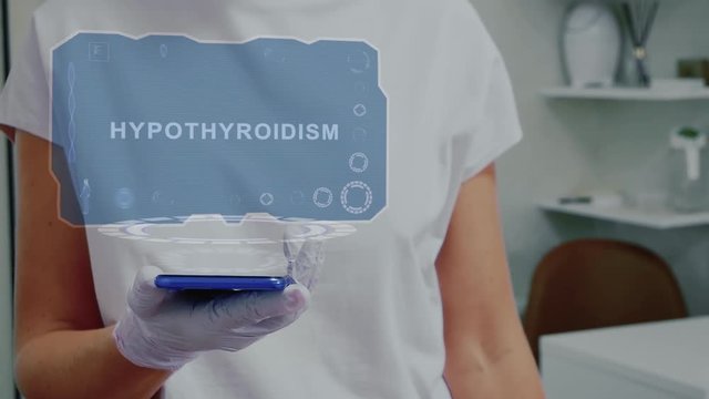 Doctor in medical glove against background of doctor's office with HUD hologram text Hypothyroidism. Hand holds futuristic holographic gadget. Medical technology concept of the future