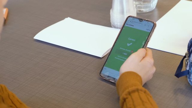 Tel Aviv, Israel - Dec 27, 2019: Israeli elementary caucasian teen girl plays "Kahoot!" with her phone in a classroom lesson. An online game-based learning platform used as educational technology.