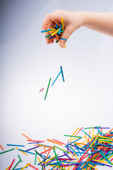 Hand letting coloured wooden  sticks drop on white