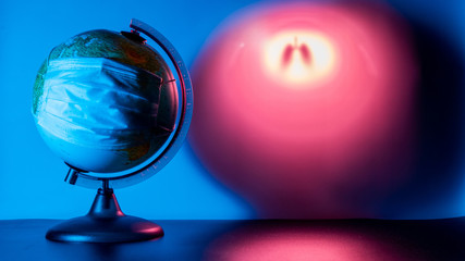 A globe of the Earth with a medical mask on it. Blue globe light. Pink gradient text field. Outlines of human lungs. Coronavirus pandemic. World medical concept. Concept of fight against virus