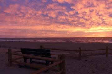 Fototapeta na wymiar Chairs On Beach Against Sky During Sunset