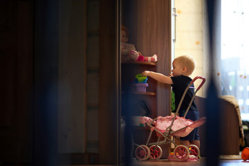 Obraz na płótnie Canvas Side view of silhouette baby boy standing by cabinet in dark room