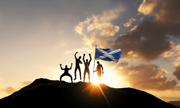 A Group Of People Celebrate On A Mountain Top With Scotland Flag. 3D Render