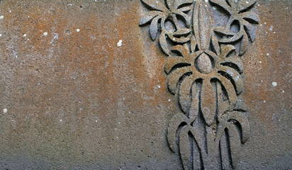 A botanical floral detail carved in a sandstone fountain basin, showing a monstera plant.