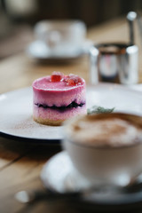 a delicious dessert of souffle and berries on a round sponge cake layer lies in a white plate sprinkled with powdered sugar. A photo with a blurred background.