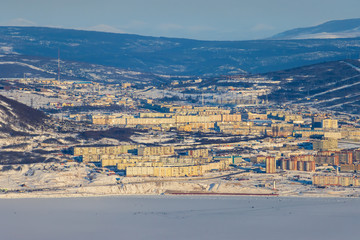 Beautiful winter view of the northern port city of Magadan. Magadan is located on the shore of the Sea of Okhotsk. City panorama with many buildings and hills. Magadan, Siberia, Far East of Russia.