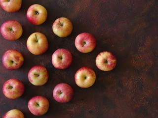 Red apples placed in a triangle on a brown background